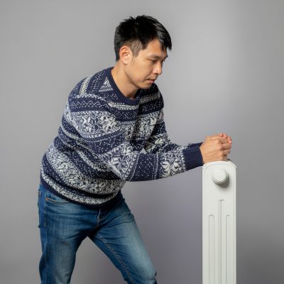 Ein Mann steht vor seinem Heizk&ouml;rper und denkt &uuml;ber Effizienz nach,
